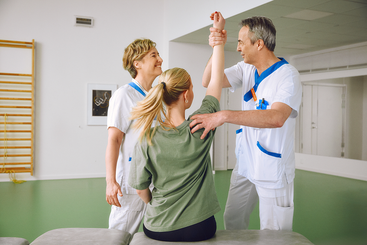 Två fysioterapeuter instruerar en patient.
