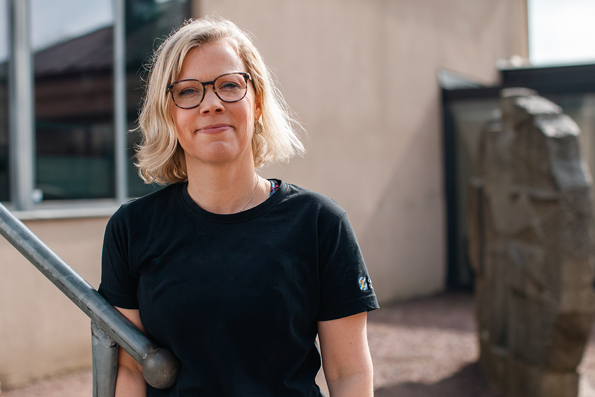 Kvinnlig fysioterapeut som står utomhus vid ett trappräcke.