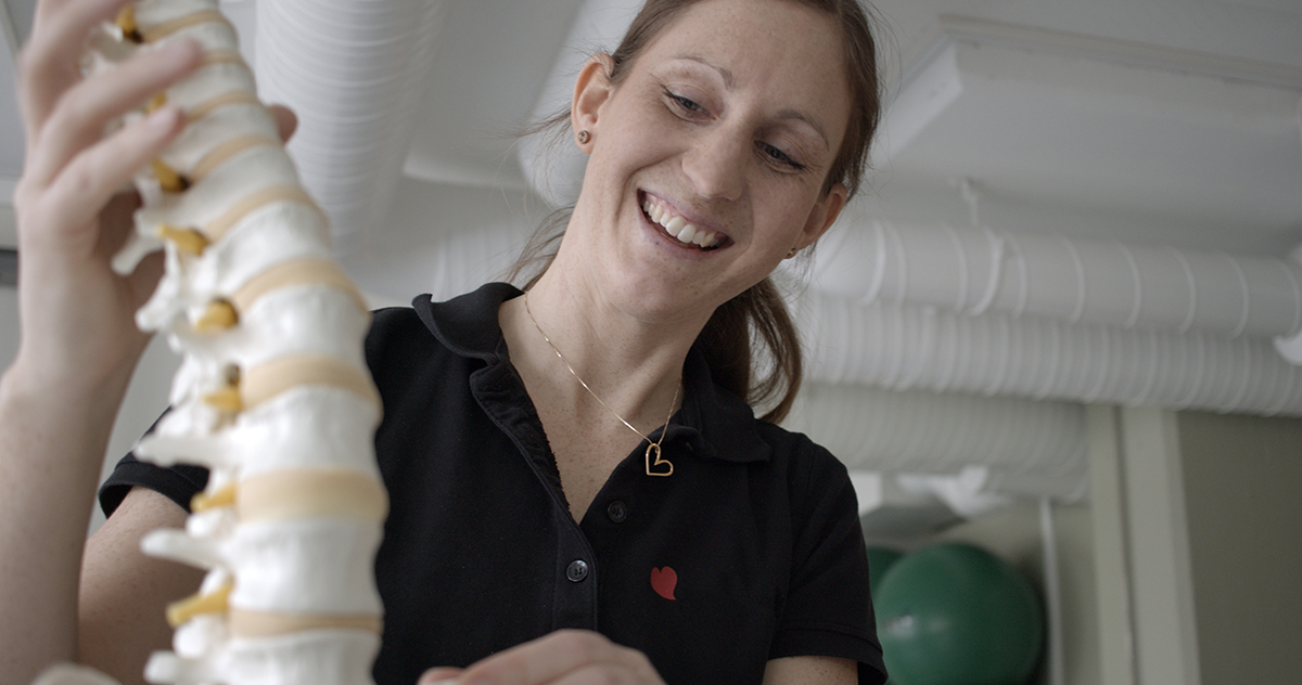 Kvinnlig fysioterapeut håller i en modell av en ryggrad.